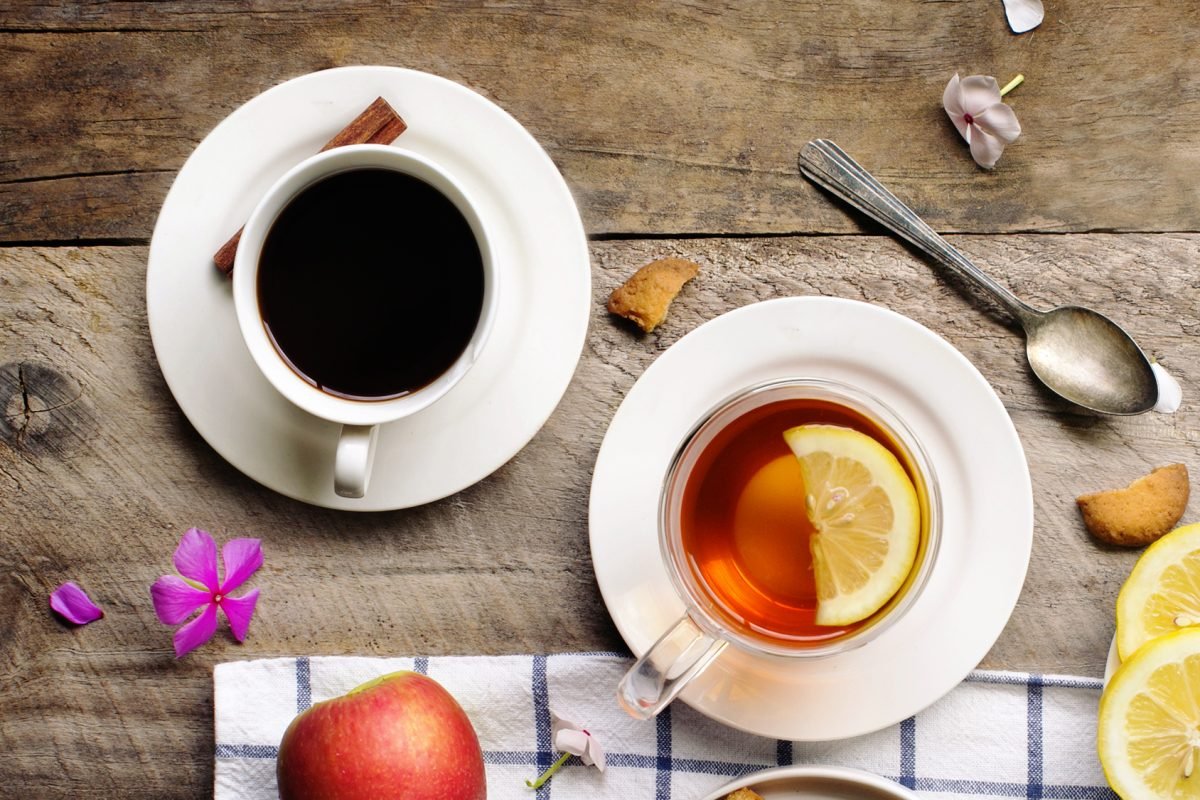 Overhead view of lemon tea and black coffee; tea or coffee break with snack food and drink table top image.